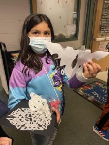 Student showing snowflake cutouts