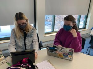 two students working on laptops in a library
