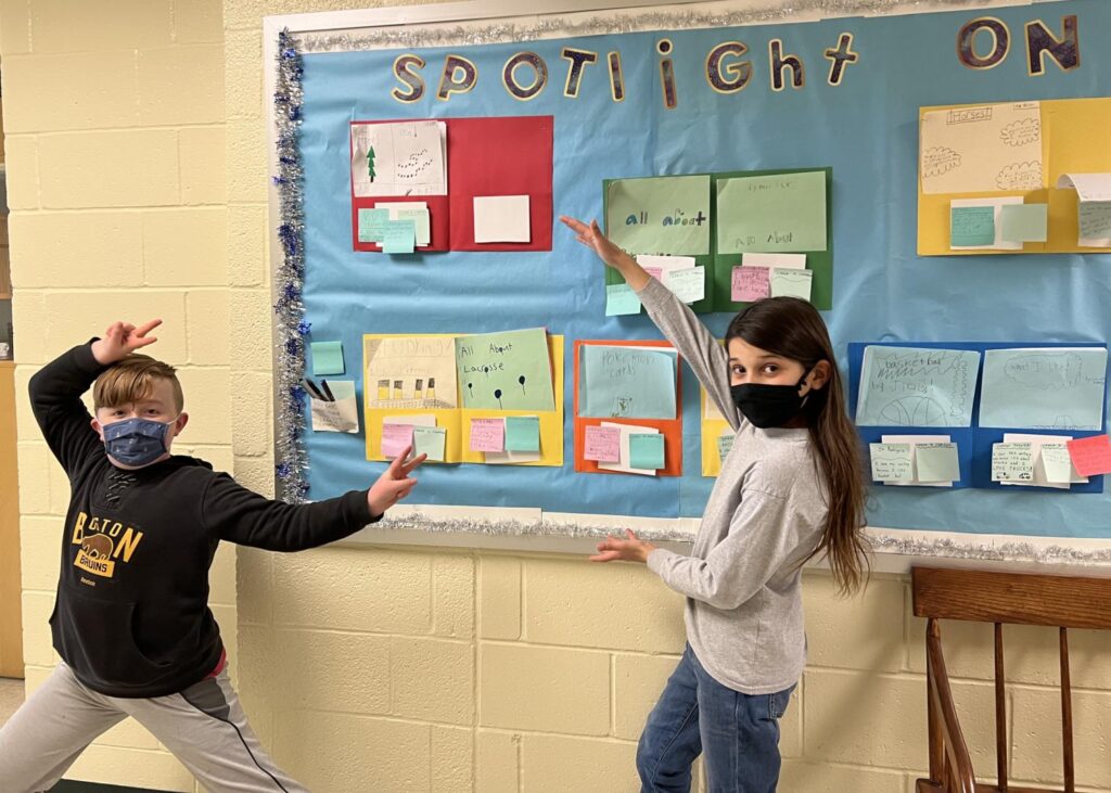 Fifth grade student team in front of the writing bulletin board