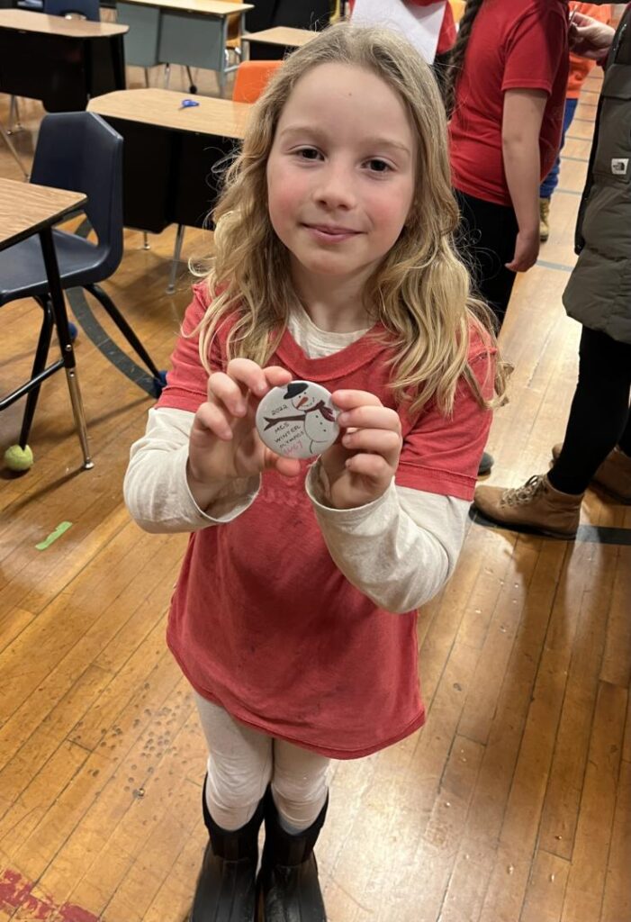 student displaying her button that she made