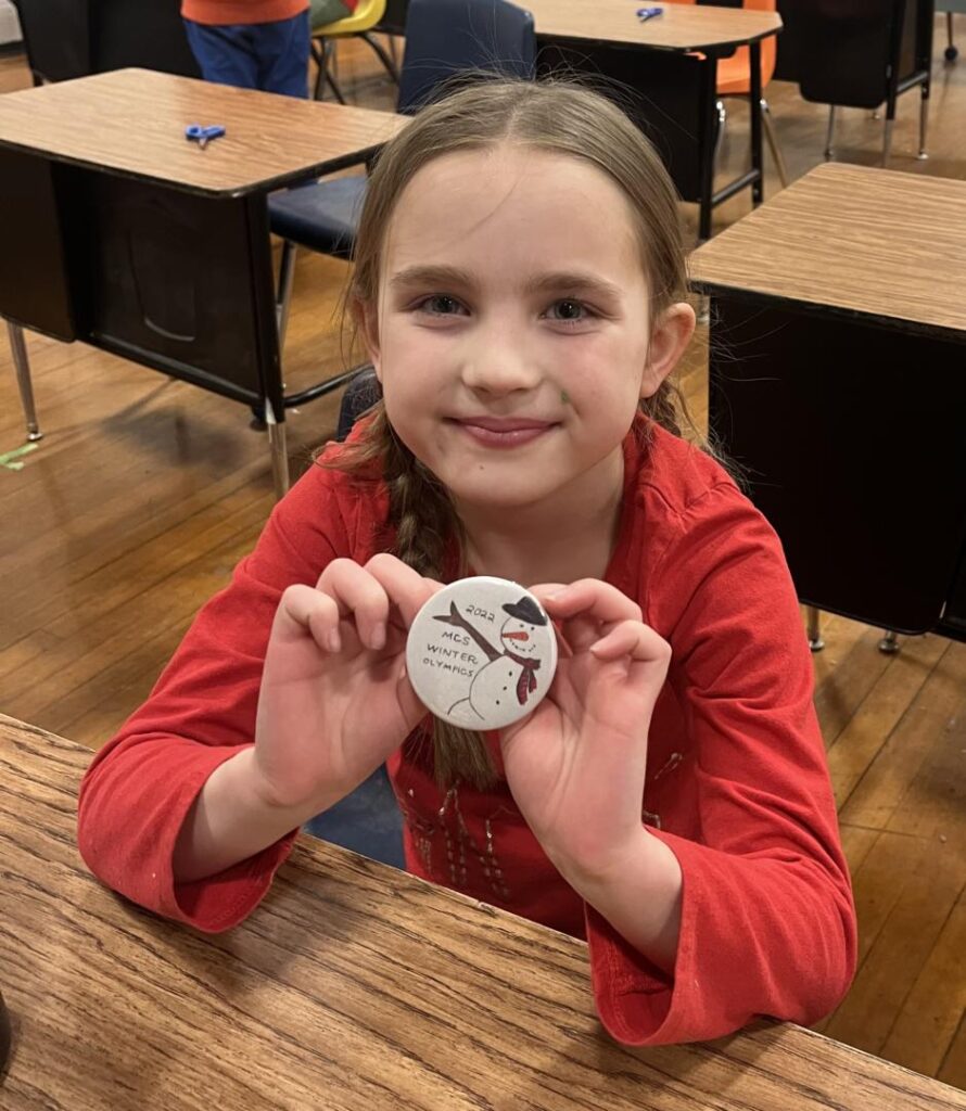 student displaying her button that she made