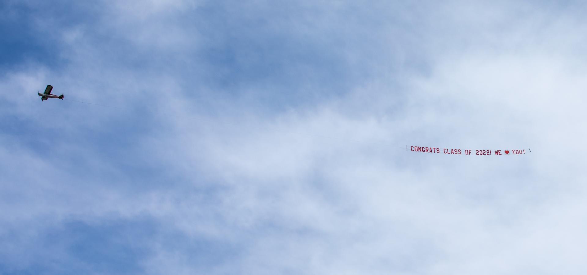 We Love MA Grads banner being flown by a plane