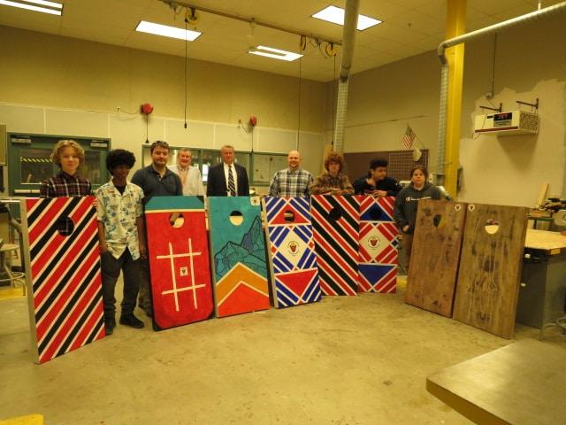 Students standing with cornhole boards they made