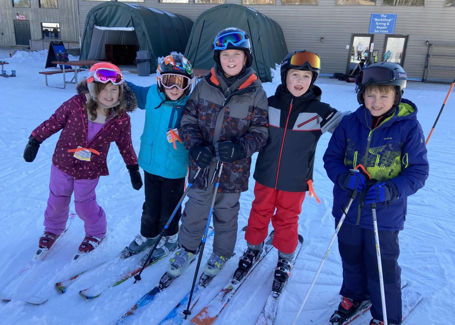 students standing together with downhill skis on