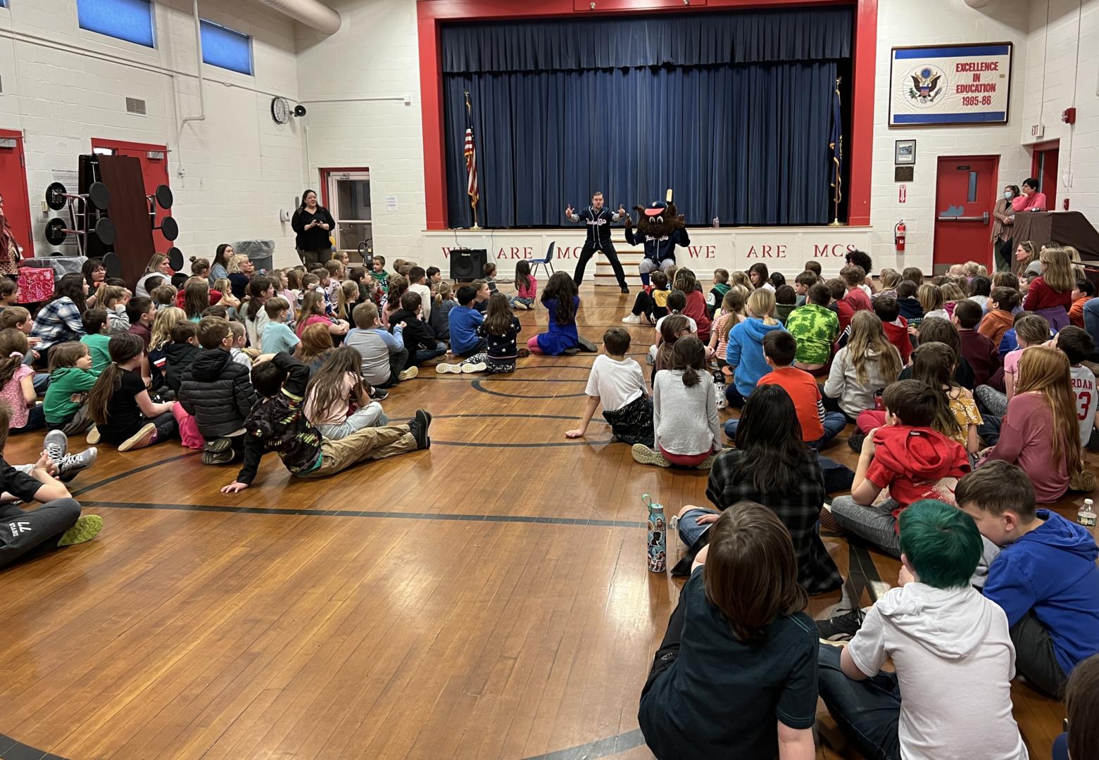 Slider and Andrew from the Fisher cats speaking to students during an assembly