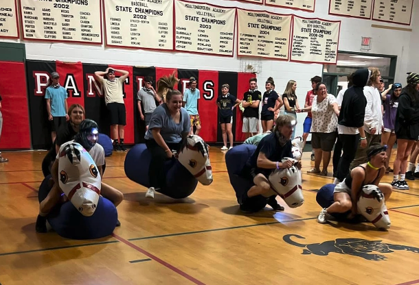students riding inflatable horses during a race at MA After Prom party 2022