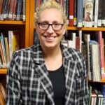 smiling woman standing in front of books