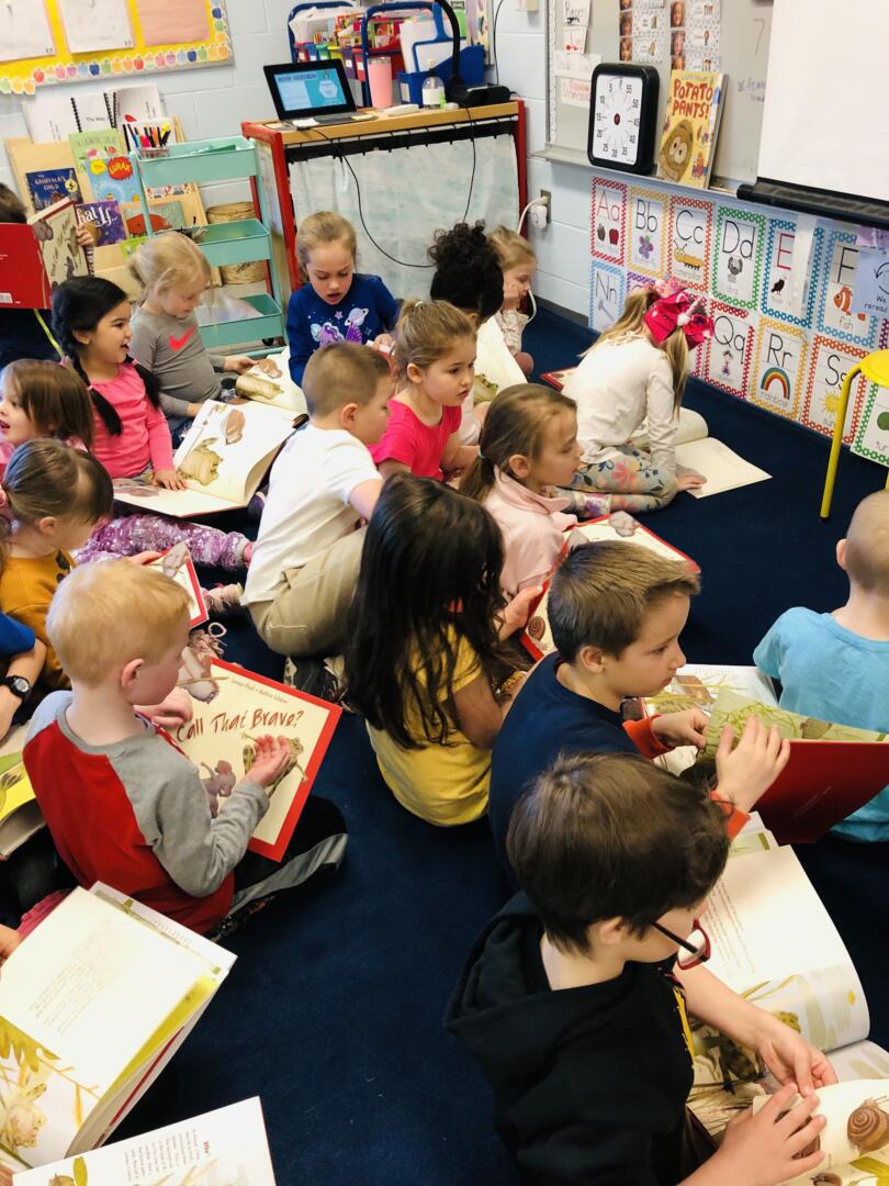 kindergarten students sitting on the floor reading books