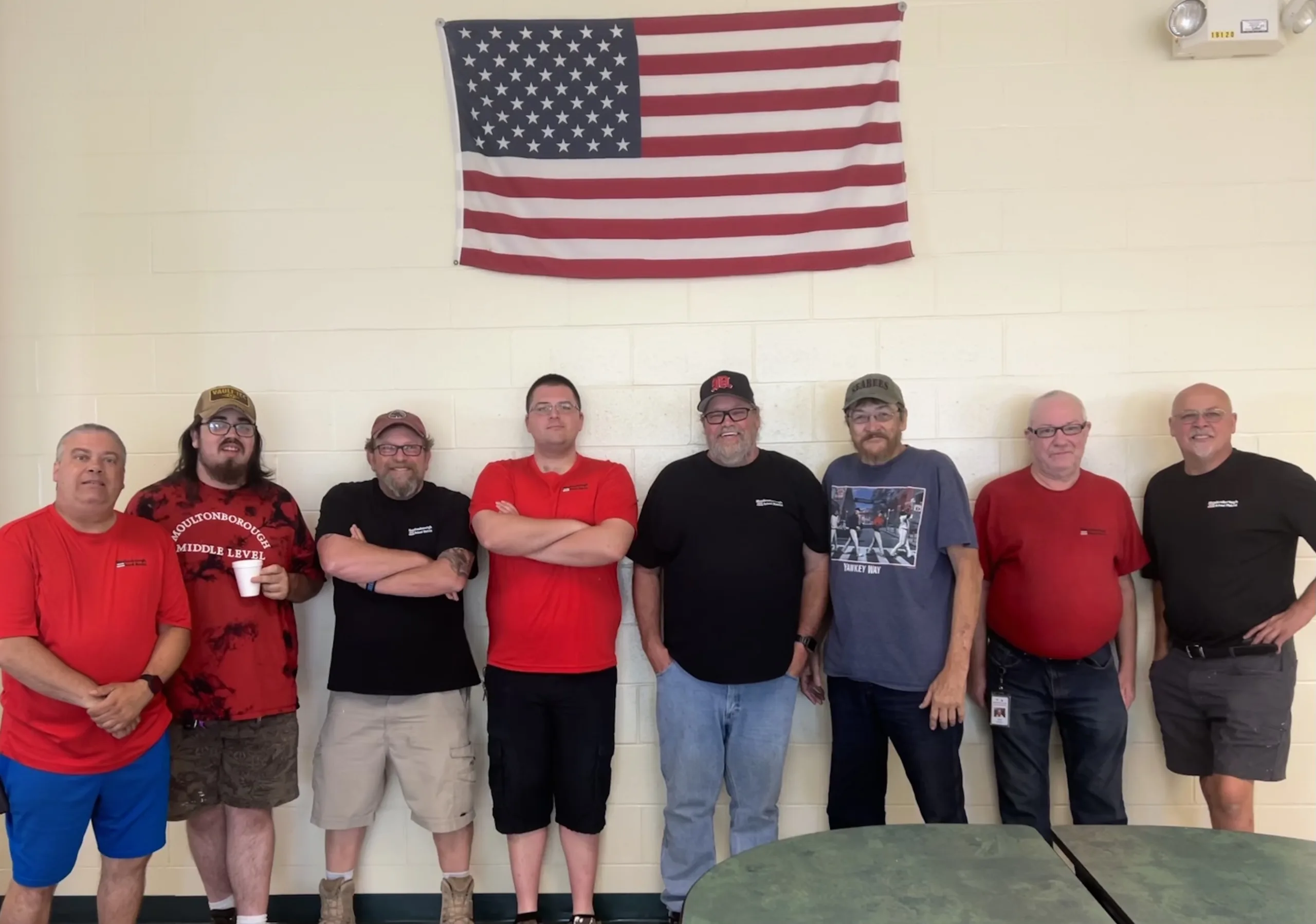 8 men standing against a white wall