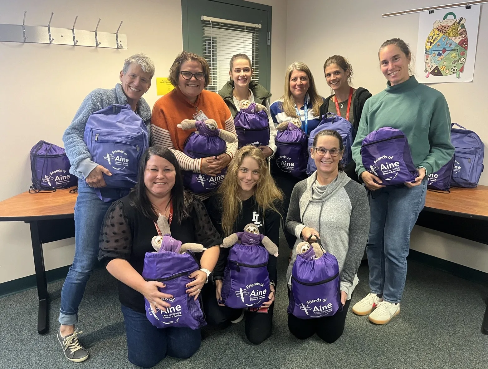 group of women holding up purple drawstring backpacks