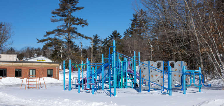 A blue playground coated in a few inches of snow.