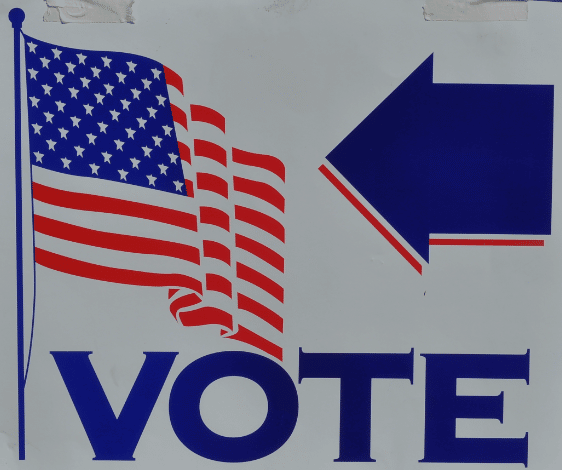 Voting sign with a blue arrow and an American Flag.