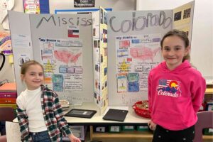 Two students standing in front of their presentations on states in the US.