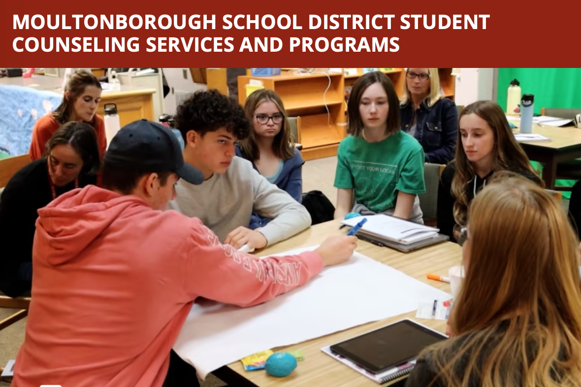 students sitting at a table writing on a poster